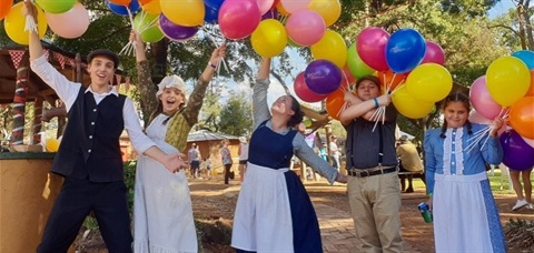 people dressed in old style clothing and holding balloons